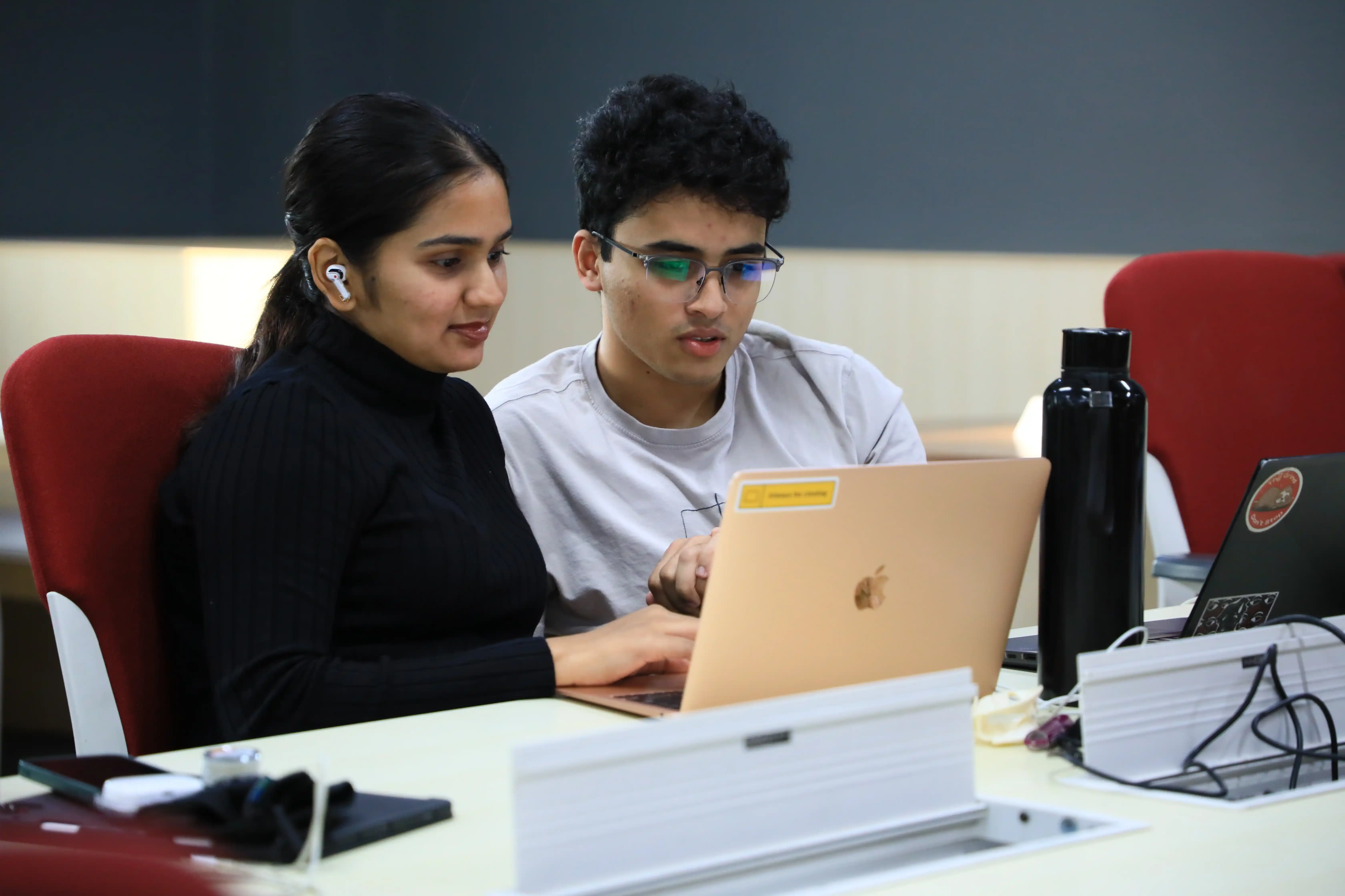 Two Economics and Data Analytics students reviewing data on a laptop together